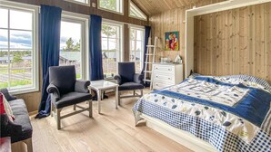 A cozy bedroom with a large bed, two armchairs, a small table, and a dresser. - 4 bedroom beautiful home in Tisleidalen (Tisleidalen)
