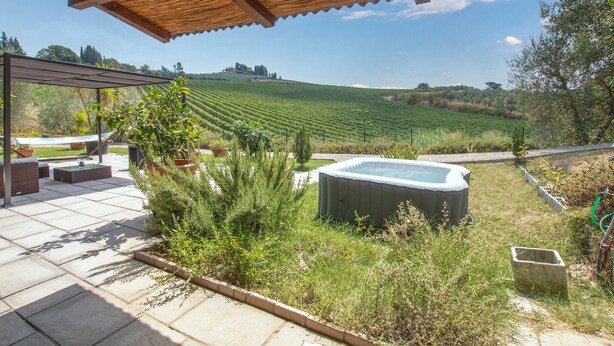 A patio area with outdoor seating, a hot tub, and a view of a vineyard.