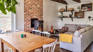 Ein gemütliches Wohnzimmer mit Kamin aus Ziegelsteinen, einem grauen Sofa und einem Holzespeisetisch.
