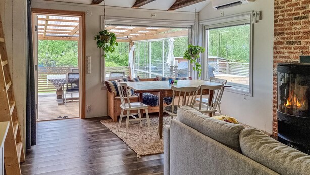 Ein gemütliches Interieur mit Essbereich, Kamin und großen Fenstern mit Blick ins Freie.