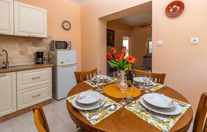 A dining area with a wooden table set for four, a white refrigerator, a microwave, and a coffee maker in the kitchen area. - 2 bedroom nice apartment in Sisan (Sisan)
