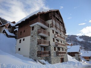 A multi-story hotel with stone and wood exterior, balconies, and a mountainous backdrop. - South-facing apartment for 4 with balcony in Valloire (Valloire)