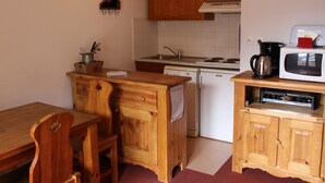 Ett kompakt kök med träskåp, en mikrovågsugn, en vattenkokare och ett handfat.