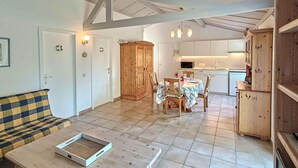 A spacious living area with a sofa, dining table, and chairs, a kitchen in the background, and a wooden cabinet. - 2 bedroom awesome home in Bredene (Bredene)