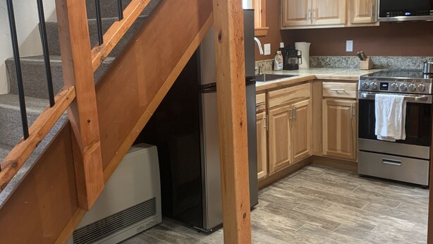 A kitchen with wooden cabinets, a stainless steel refrigerator, a microwave, and an oven. - VRBO unit in private home, in town with ocean views (Homer)