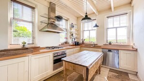 Una cocina con armarios blancos, una mesa de madera, una estufa y un lavavajillas.