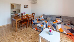 A living room with a sofa, a coffee table, and a dining area with chairs and a table.