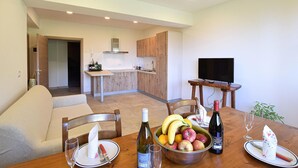 A dining area with a table set for two, a kitchen in the background, and a TV mounted on the wall. - Gorgeous apartment in Lamon with WiFi (Lamon)