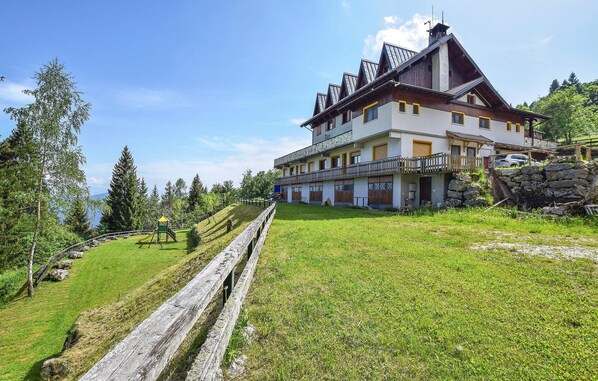 A multi-story building with a balcony, surrounded by a grassy area and trees. - Gorgeous apartment in Lamon with WiFi (Lamon)