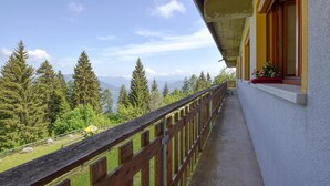 A balcony with a wooden railing overlooking a mountainous landscape with evergreen trees. - Gorgeous apartment in Lamon with WiFi (Lamon)