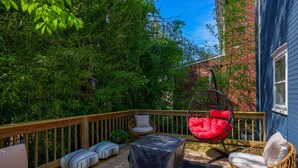 Um terraço com móveis de exterior, incluindo um sofá, cadeiras e uma cadeira suspensa.