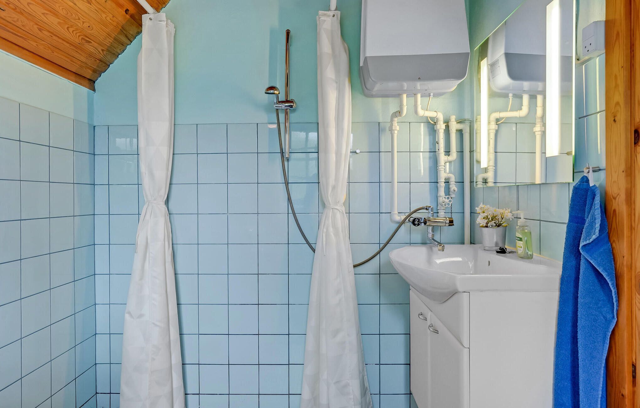 Une salle de bain avec une douche, un lavabo et un miroir.