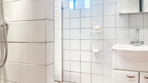A bathroom with white tiles, a shower, a toilet, and a sink with a mirror above it. - Beautiful (sta)caravan in Bergen aan Zee with WiFi (Bergen aan Zee)