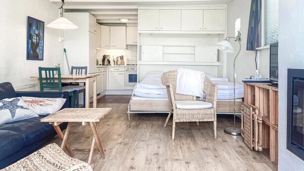 A compact living space with a kitchenette, a dining area, a bed, and a seating area with a sofa and chairs. - Beautiful (sta)caravan in Bergen aan Zee with WiFi (Bergen aan Zee)