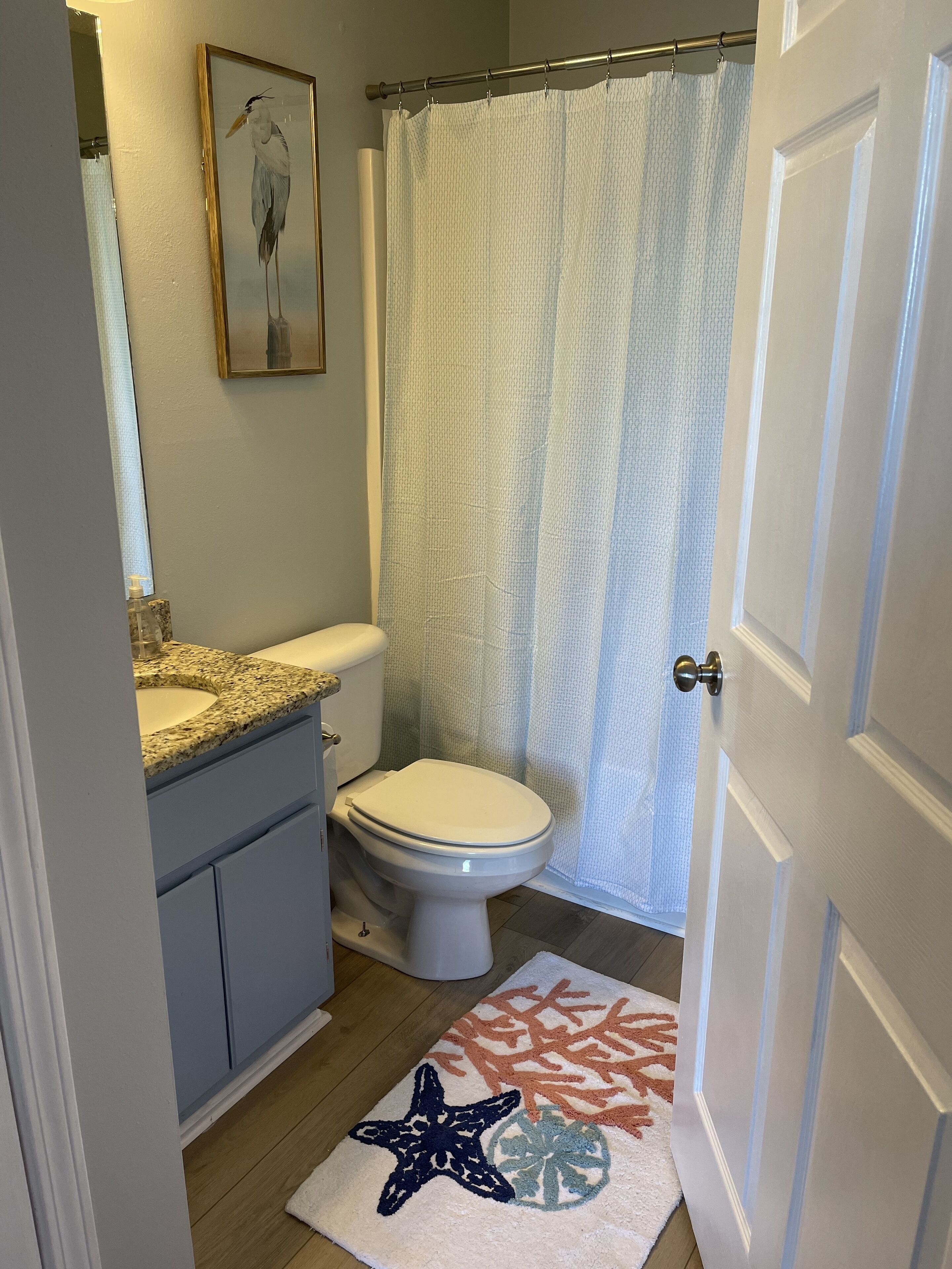 A bathroom with a toilet, sink, and shower curtain.