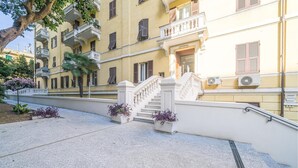 A building with a white staircase, balconies, and a yellow facade.
