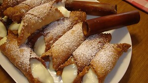 Um prato de cannoli com palitos de chocolate e açúcar em pó.