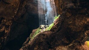 A cave with a natural rock formation and a narrow opening allowing light to enter. - Cenote Pueblo Fantasma (Chemax)