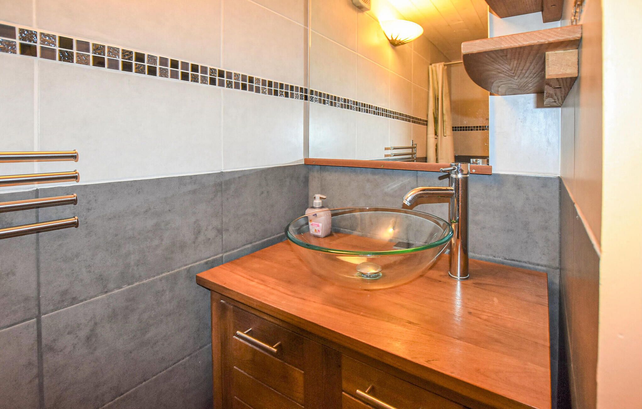 Ein Badezimmer mit einem Waschbecken aus Glas, einem Holzwaschtisch und einem Spiegel darüber.