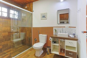 A bathroom with a glass shower enclosure, a toilet, and a sink with a mirror above it. - LoftS Campos 01 (Campos do Jordão)