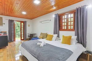 A bedroom with a wooden ceiling, a bed with a grey and white duvet, and a window with curtains. - LoftS Campos 01 (Campos do Jordão)