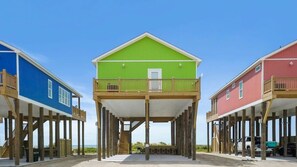 A beachfront property with three elevated structures, each featuring a balcony and a staircase leading to a deck. - Beachfront Home•Steps to Sand•Sleeps 10 (Bolivar Peninsula)
