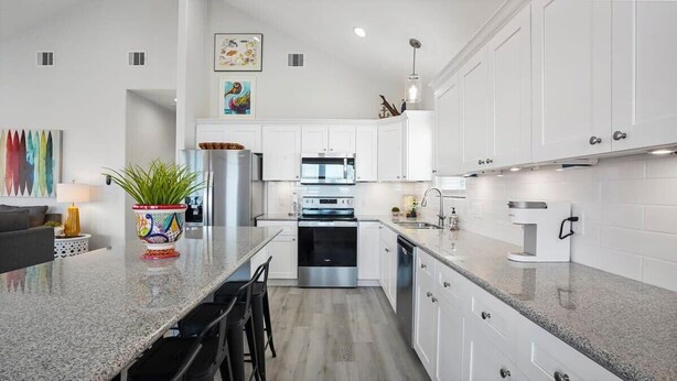 A modern kitchen with white cabinets, stainless steel appliances, and a granite countertop. - Beachfront Home•Steps to Sand•Sleeps 10 (Bolivar Peninsula)
