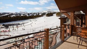 Estación de esquí con vistas a una montaña nevada y una zona de piscina.