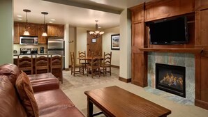 Una sala de estar con chimenea, un televisor montado sobre ella y un comedor con muebles de madera.