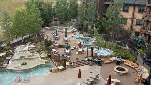 Un resort con varios jacuzzis, mobiliario exterior y zona de piscina.