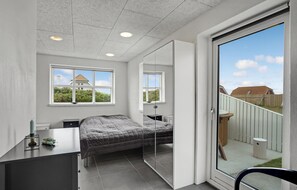 A bedroom with a bed, a desk, a chair, and a sliding glass door leading to a balcony. - Lovely home in Vestervig with sauna (Vestervig)