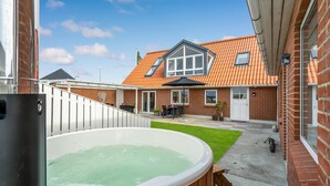 A backyard with a hot tub, a patio with outdoor furniture, and a brick house with a tiled roof. - Lovely home in Vestervig with sauna (Vestervig)