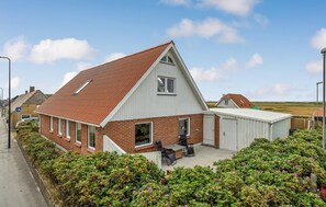 A two-story house with a red-tiled roof, a large front window, and a small attached garage. - Lovely home in Vestervig with sauna (Vestervig)