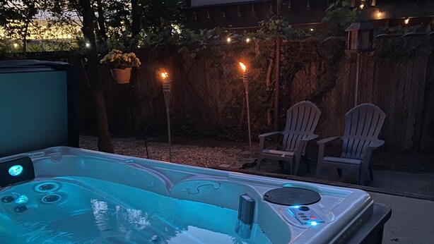 Ein Whirlpool mit Düsen, umgeben von einem Holzzaun und Gartenmöbeln.