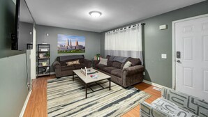 Ein Wohnzimmer mit zwei Sofas, einem Couchtisch, einem Fernseher und einem Gemälde an der Wand.