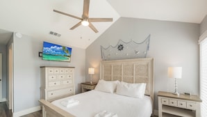 A bedroom with a bed, nightstands, a ceiling fan, a TV, and a decorative wall piece. - Poolside Condo | Modern Charm, Heated Pool & Steps to Beach (Corpus Christi)