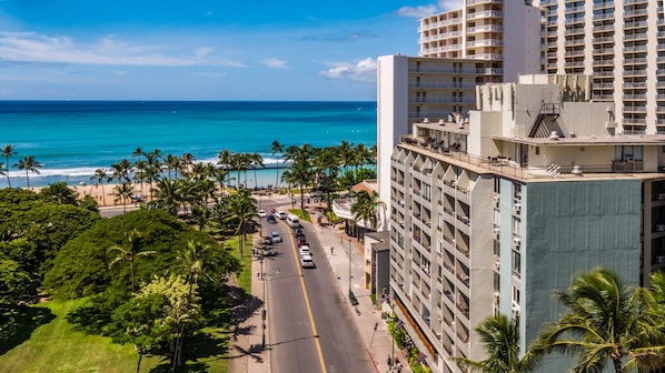 Un hôtel avec vue sur la plage et l’océan, comprenant plusieurs étages, des balcons et un espace de stationnement.