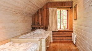 Une chambre de cabine avec deux lits en bois, une fenêtre avec des rideaux et un radiateur au mur.