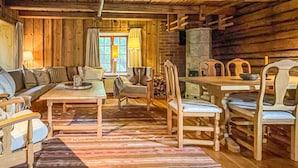 L’intérieur d’un chalet chaleureux, avec une table à manger en bois, un canapé et une cheminée.