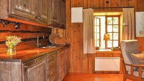 L’intérieur d’un chalet rustique, avec des murs en bois, une table à manger en bois, un évier et une chaise.