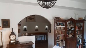 A room with a wooden desk, a bookshelf, a bed, and a dining area with a counter and stools. - The traveler's choice (Genova)