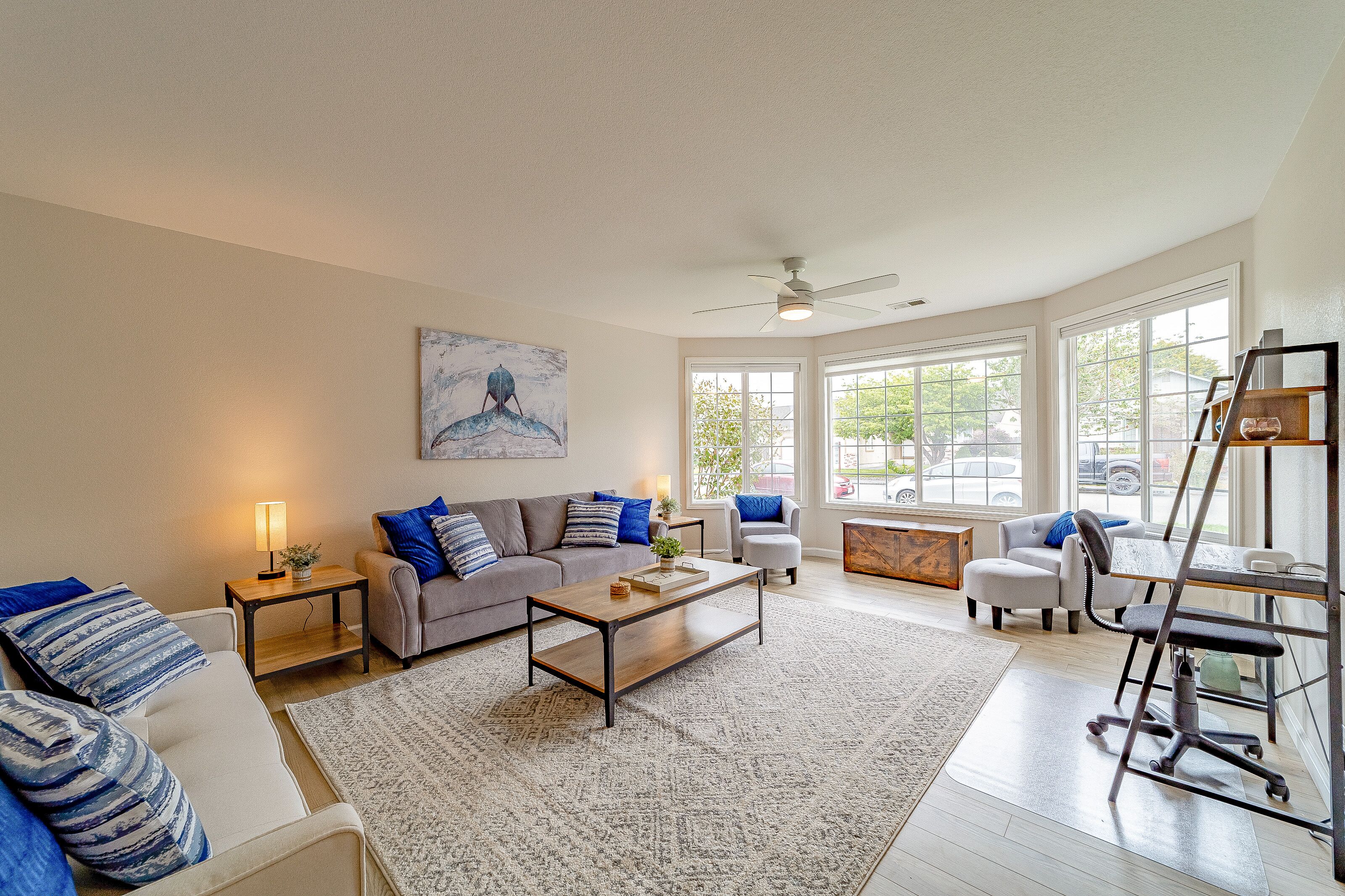 A spacious living room with a gray sofa, a wooden coffee table, and a white armchair.