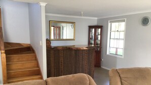 Una sala de estar con una escalera de madera, una barra de bar de madera y un espejo grande en la pared.
