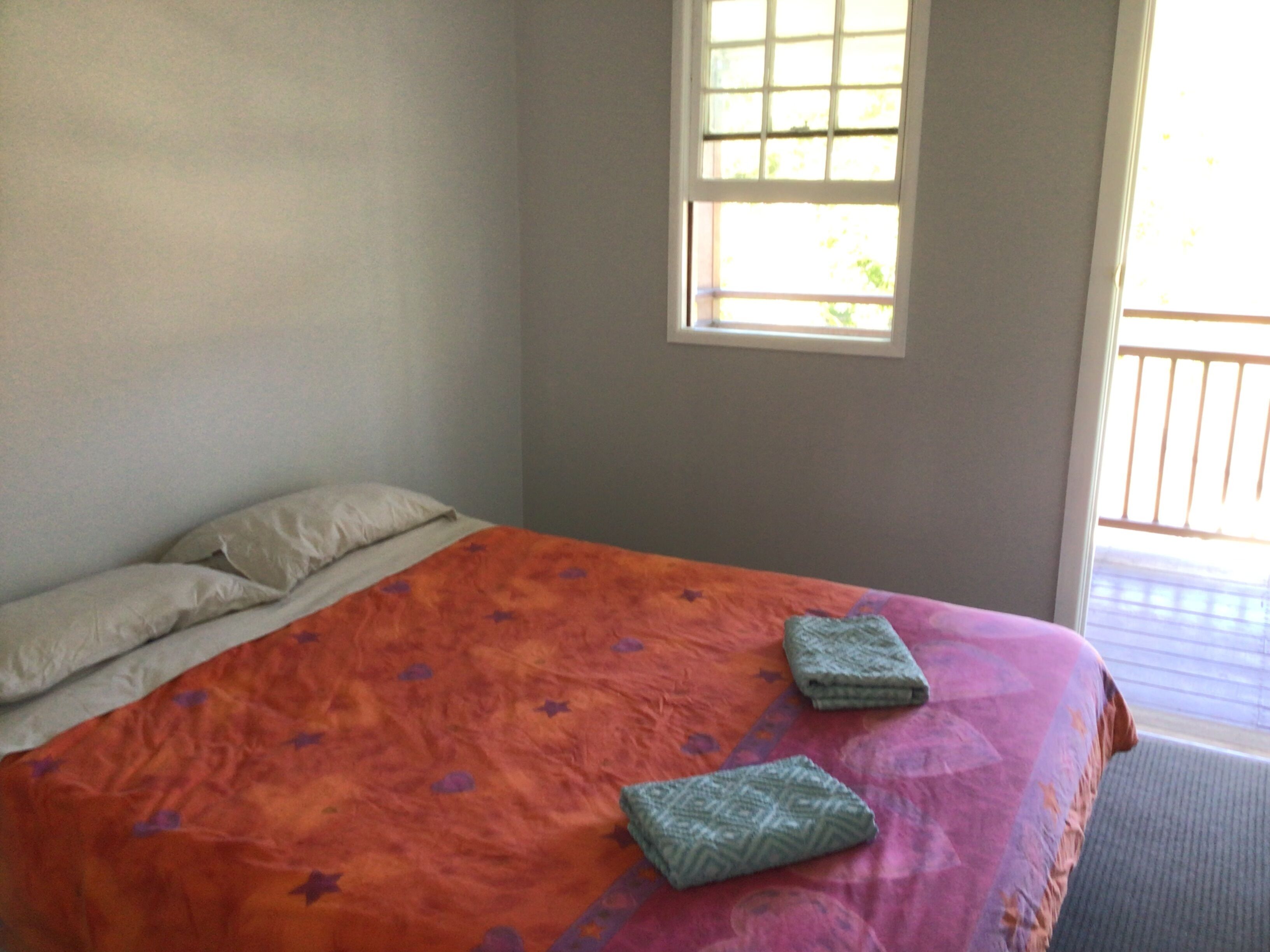 Een slaapkamer met een bed, kussens en een raam.