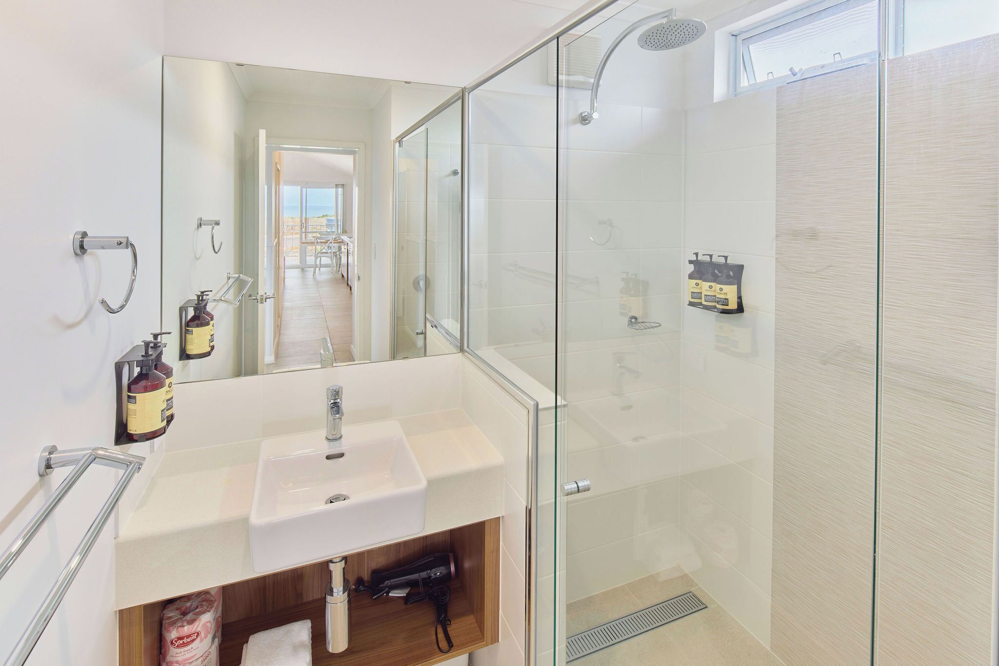 A modern bathroom with a glass shower enclosure, a white sink, and a mirror.
