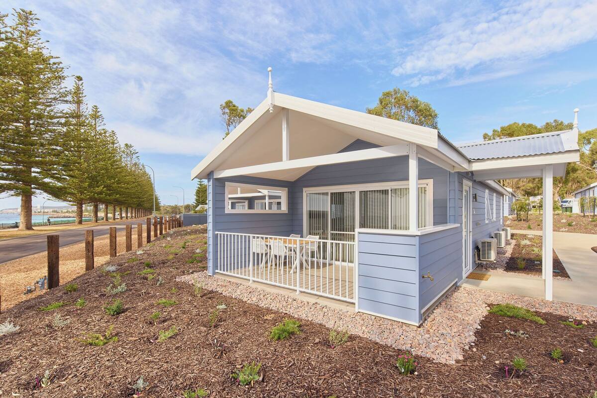 A small, single-story house with a porch and a covered outdoor seating area.