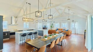 A spacious kitchen with a central island, wooden flooring, and pendant lighting. - RAC Esperance Holiday Park (Castletown)