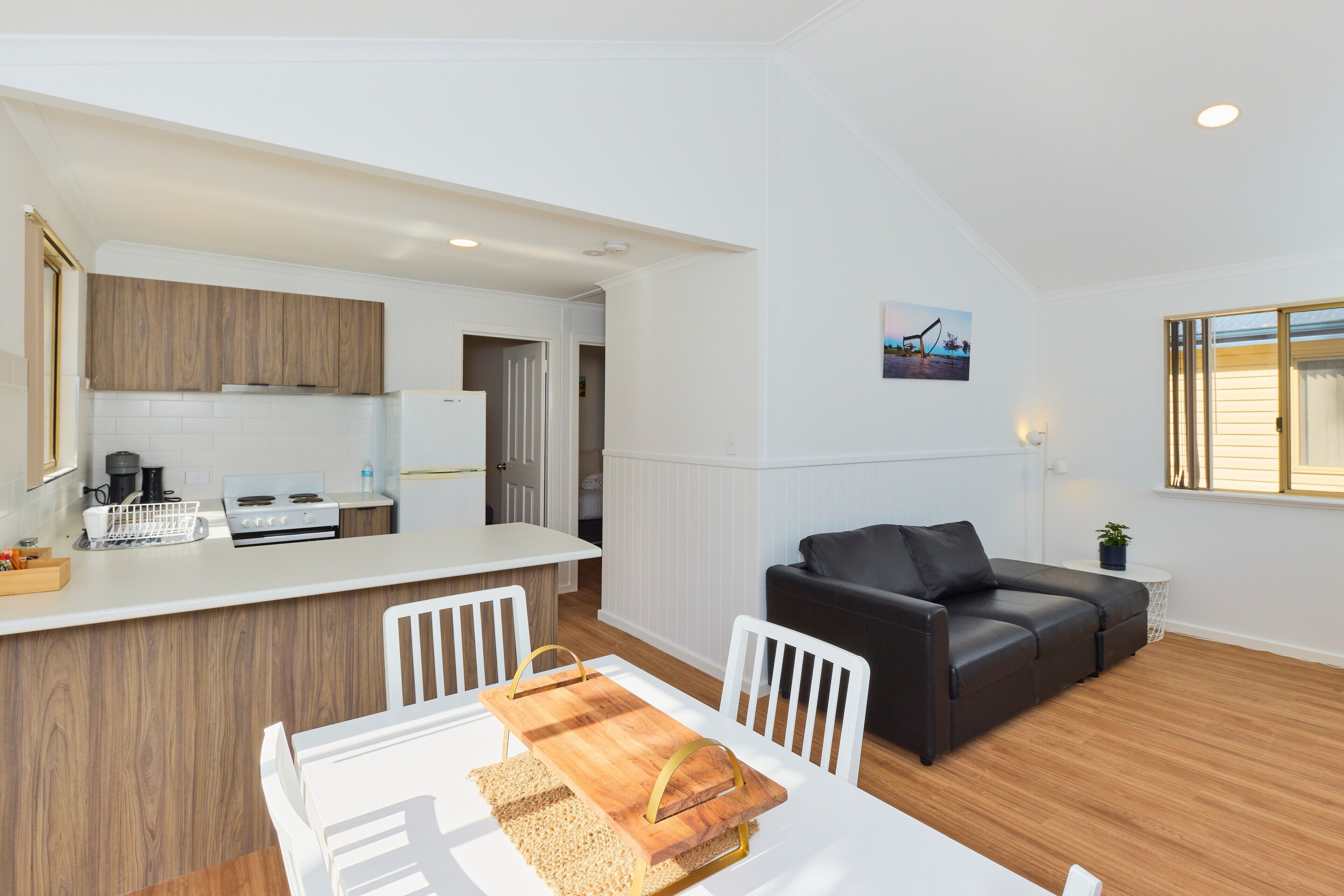 A modern kitchen with white cabinets, a wooden countertop, and a dining area with a white table and chairs.
