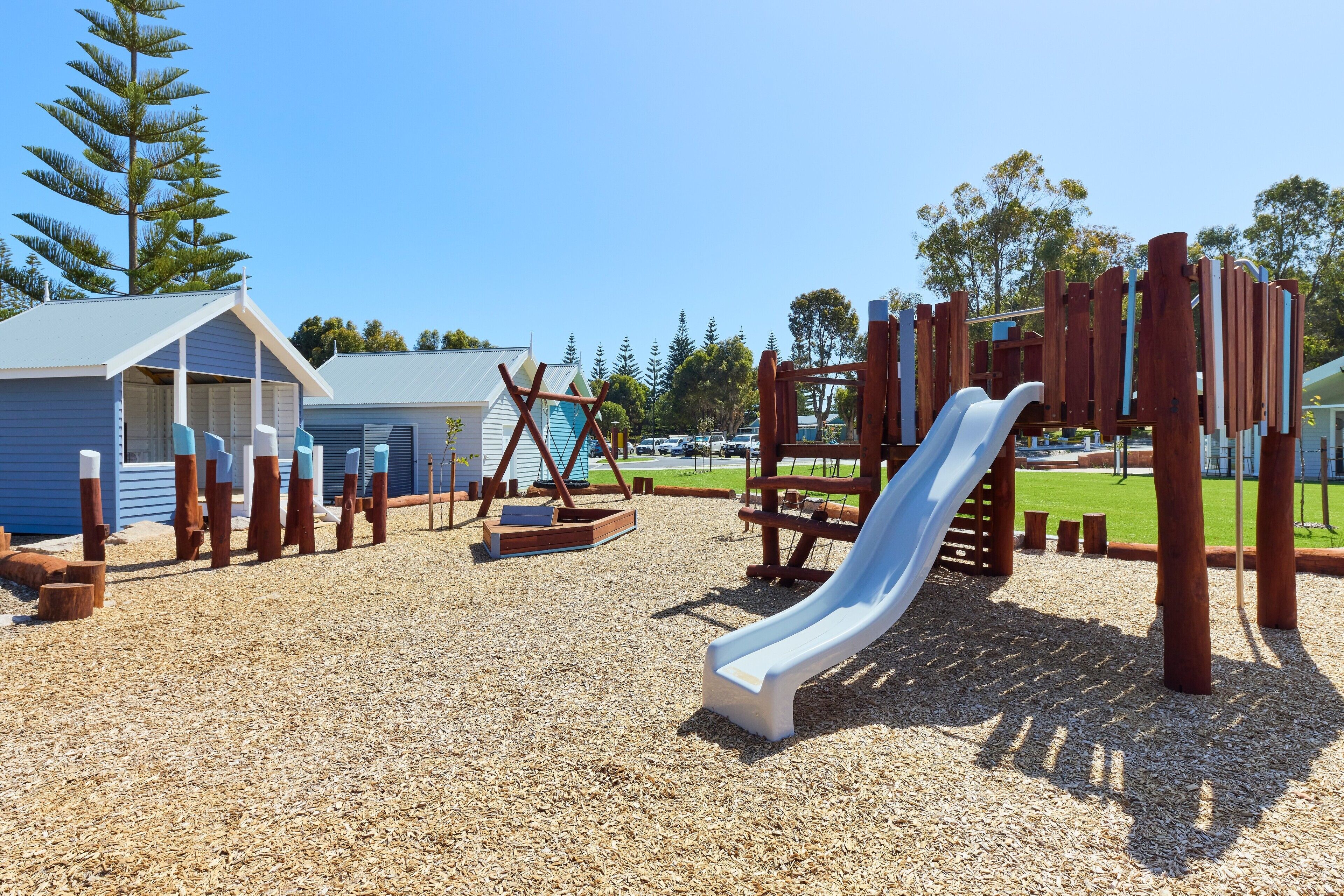 A playground with a slide, climbing structures, and a small building.