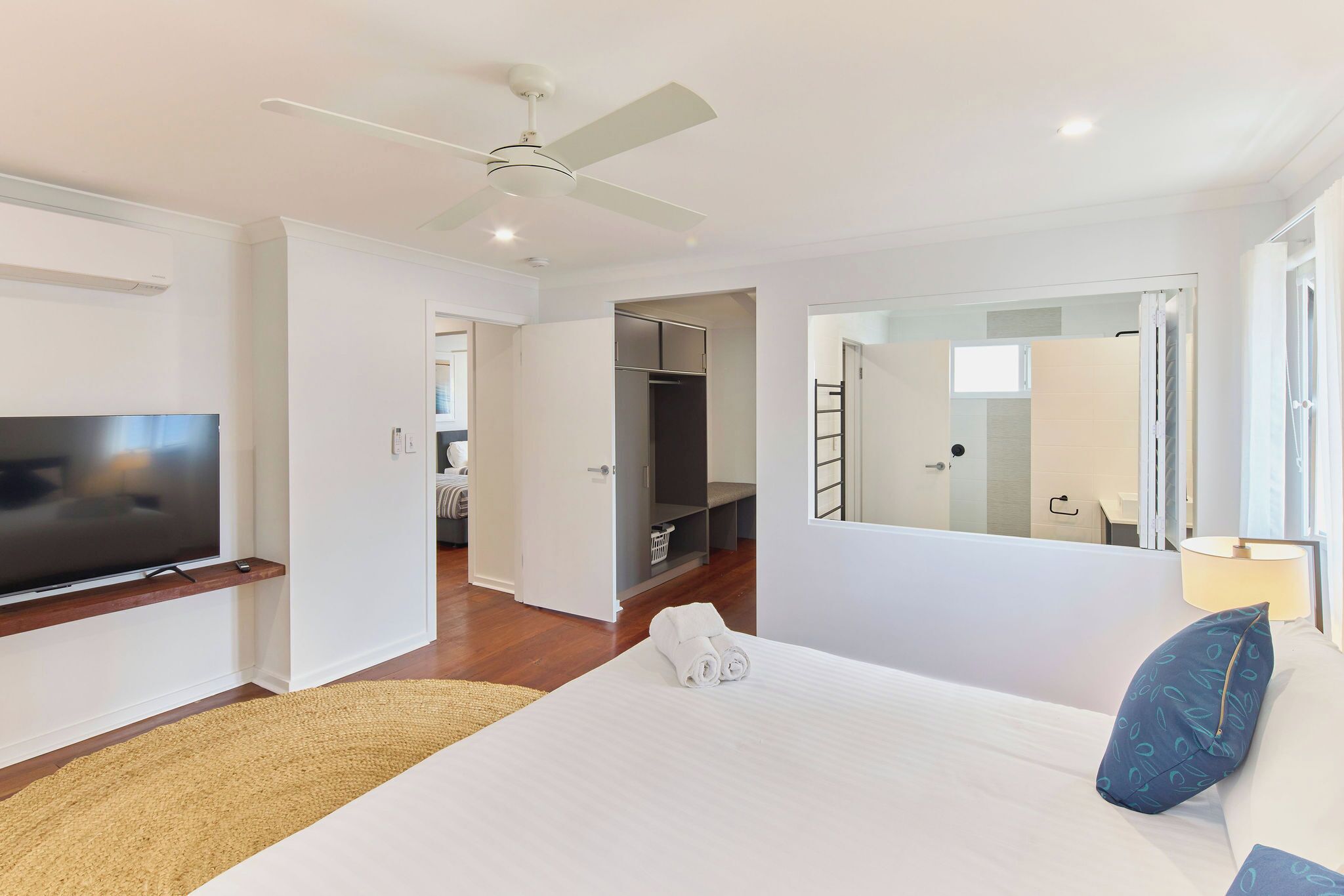 Une chambre d’hôtel avec un lit, une télévision, un ventilateur de plafond, une armoire et une salle de bain visible à travers une porte ouverte.